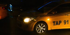 Gele taxi met brandende koplamp in de avond